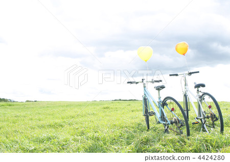 Two bicycles with a balloon lining the grassland 4424280