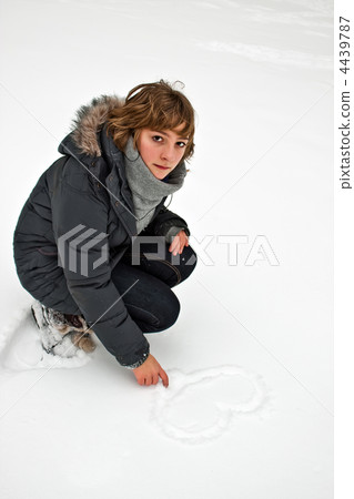 The girl draws a heart in the snow. 4439787