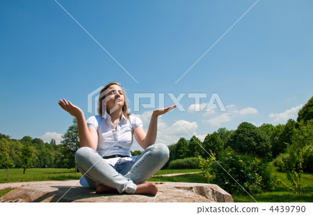 Young girl sitting on a felled tree and meditating. Young girl sitting on a felled tree and meditating. 4439790
