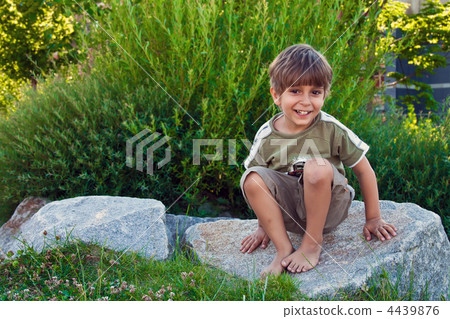 Portrait of a young boy, sitting on a rock. 4439876