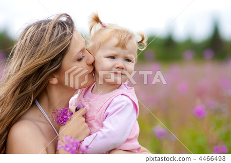 Mother kissing daughter in meadow outdoor Mother kissing daughter in meadow outdoor 4466498