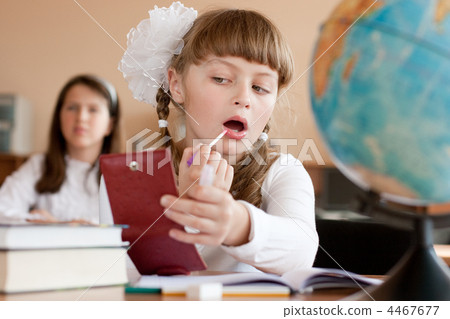 Cute preteen schoolgirl is making make-up during lesson at schoo Cute preteen schoolgirl is making make-up during lesson at schoo 4467677