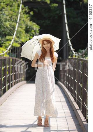 A woman putting a white parasol in a suspended bridge A woman putting a white parasol in a suspended bridge 4468327