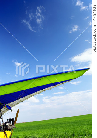 Motorized hang glider over green grass 4484638