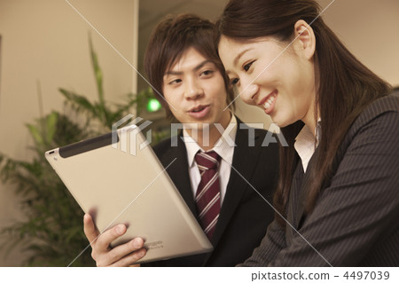 Male and female businessmen talking while watching a tablet terminal 4497039