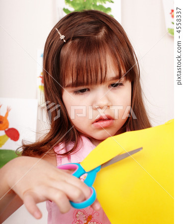 Child with scissors cut paper in play room. 4558337