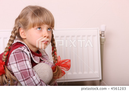 Sad girl sitting near heater. Children problem. 4561283