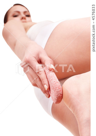 Woman rubbing heel of foot with pumice stone. 4576833