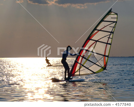 A women is learning windsurfing at the sunset 4577840