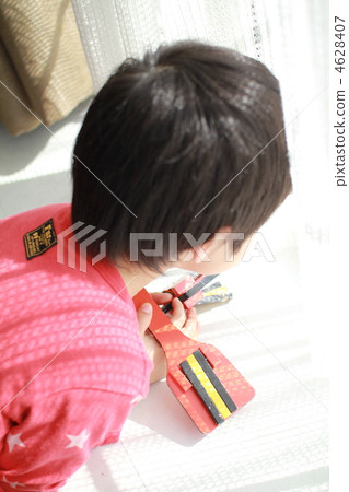 A boy holding a clapper and trying to look out the window 4628407