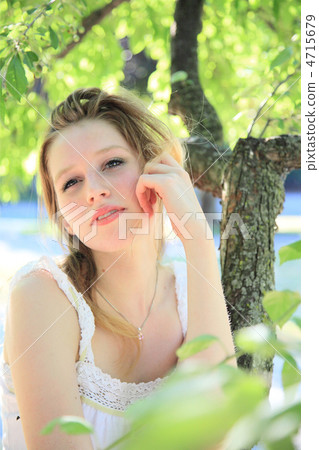 A foreign woman smiling under a tree (before editing) 4715679