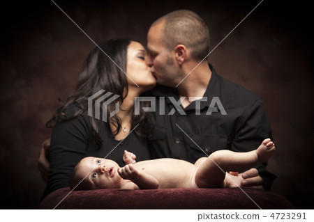 Mixed Race Couple Kiss While Baby Lays on Pillow Mixed Race Couple Kiss While Baby Lays on Pillow 4723291