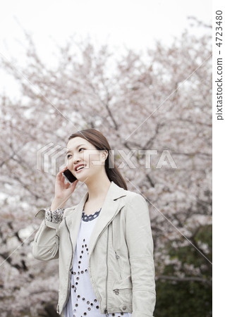 A woman talking on smartphone with cherry blossoms back A woman talking on smartphone with cherry blossoms back 4723480