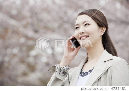 A woman talking on smartphone with cherry blossoms back A woman talking on smartphone with cherry blossoms back 4723481