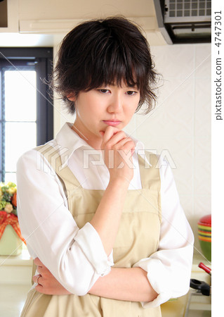 A woman in an apron who is suffering from the kitchen 4747301