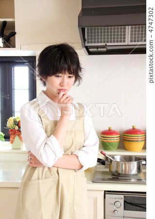 A woman in an apron who is suffering from the kitchen 4747302