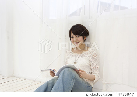 A woman sits on the floor and opens a magazine 4755947
