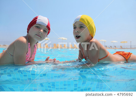 Two girls lie in  day-time in  pool opposite each other and spea 4795692
