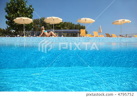 Woman becomes tanned near pool under open-skies in day-time ne Woman becomes tanned near pool under open-skies in day-time ne 4795752