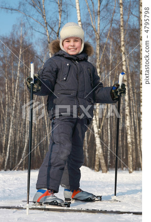 Young boy stands on cross-country skis inside winter forest at s 4795798