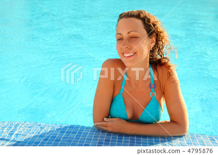 Smiling girl in blue bikini with brown curly hair stands in swim 4795876
