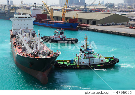 Two small boats docked to industrial ship in port at sunny day 4796035