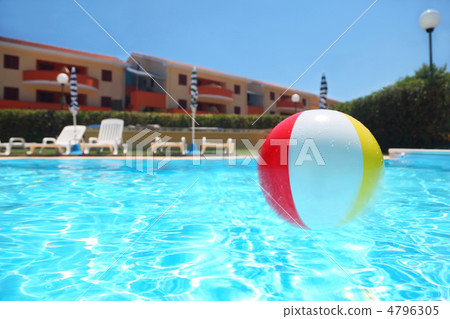 An inflatable ball lies in  pool under open-skies near cottages, 4796305