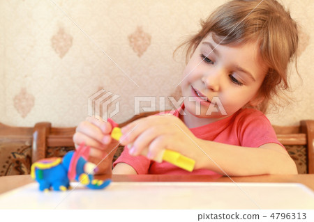 Little girl is at table and models from plasticine, focus on g Little girl is at table and models from plasticine, focus on g 4796313