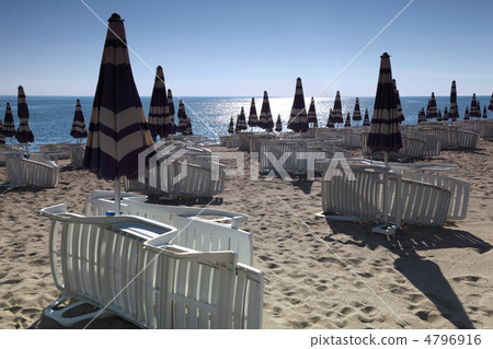 Shizlongi neatly built near the closed beach umbrellas in the mo 4796916