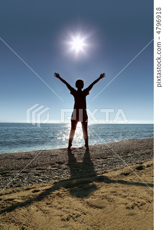 Woman stands on toes ashore  opposite  sun , heaving up hands up 4796918