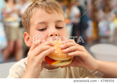 little caucasian boy eating burger, looking down little caucasian boy eating burger, looking down 4796956