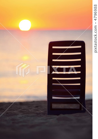 Dark blue plastic chair stands on  beach near  sea during sunset 4796988