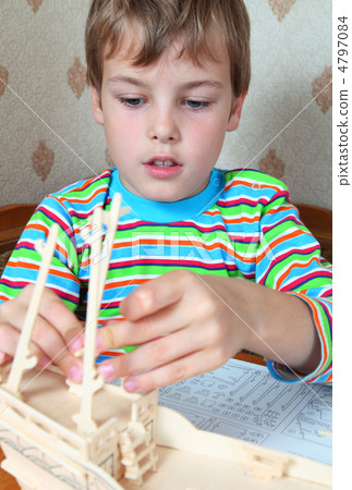 Zealous blonde boy in striped shirt make homemade wooden boat Zealous blonde boy in striped shirt make homemade wooden boat 4797084
