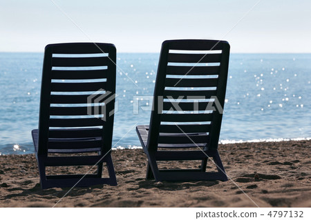 Two plastic empty chairs stand on  beach near  sea in kontrazhur 4797132