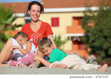 Pigeon pair play with  mother on  beach on sand, lying for it on 4797147