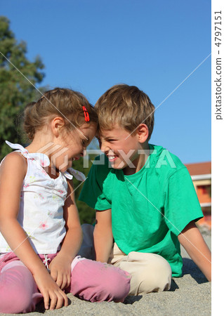 Girl and boy sit on sand by  sun day and play butted heads 4797151