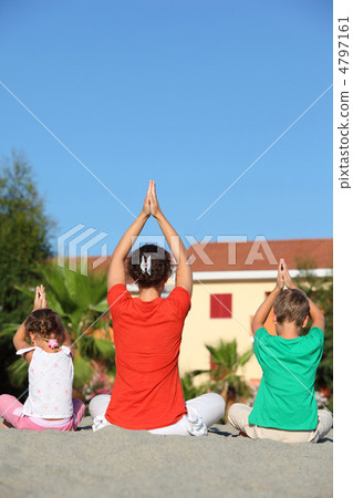 Woman with two children sit turn back on sand in pose of yoga Woman with two children sit turn back on sand in pose of yoga 4797161
