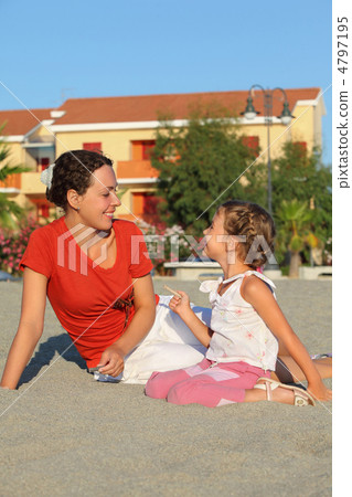 Mother with daughter sit on sand and laugh near two-storeyed cot 4797195