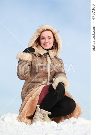 Young woman squatting on snow and holds hood hand Young woman squatting on snow and holds hood hand 4797369