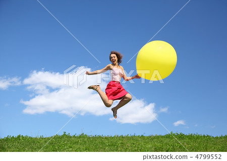 Woman jumps away from grass with large inflatable ball and laugh 4799552