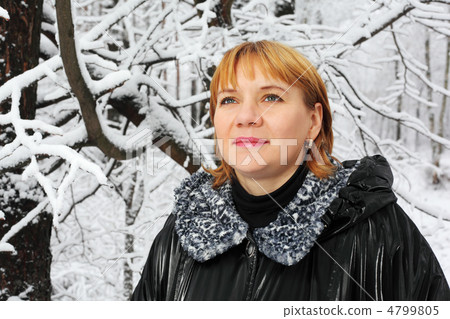 Red-headed woman dressed black jacket look up in woods in snow a Red-headed woman dressed black jacket look up in woods in snow a 4799805