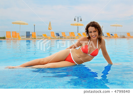 beautiful young woman in red bathing suit sitting in pool. yello 4799840