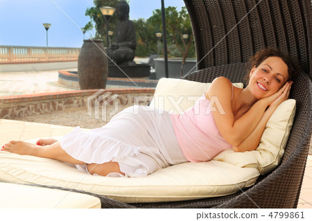 beautiful young woman lying on white cushions in black wicker ch 4799861
