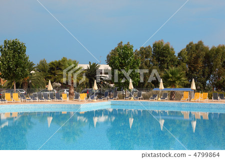 Big blue pool, yellow loungers and white parasol standing near t 4799864