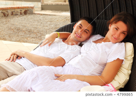 young husband and wife in white dress sitting on black wicker ch 4799865