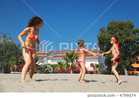 mother with her son and daughter plays in blindman's buff on bea 4799874