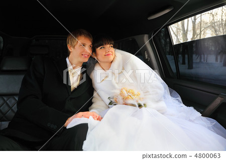 happy groom and bride with bouquet sitting inside wedding limous happy groom and bride with bouquet sitting inside wedding limous 4800063