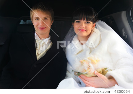 smiling groom and bride with bouquet sitting inside wedding limo smiling groom and bride with bouquet sitting inside wedding limo 4800064