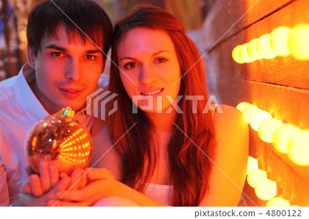 Young man and woman stand near wall with small lamps and hold Ch Young man and woman stand near wall with small lamps and hold Ch 4800122