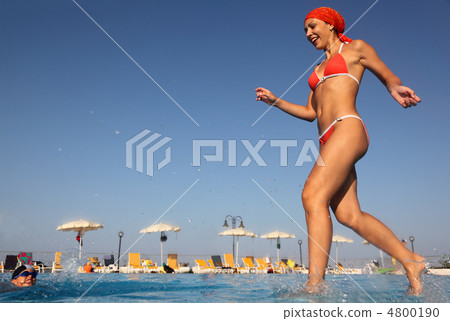 beautiful young woman in red swimsuit runs and dives into blue, 4800190